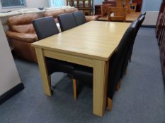 A contemporary light oak dining table and six black leather chairs