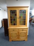 A continental light oak glazed cabinet