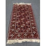 A fringed Afghan Bokhara rug on red ground,