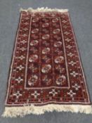 A fringed Afghan Bokhara rug on red ground,