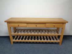 A contemporary light oak kitchen three drawer side table with under stretcher
