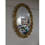 A contemporary ornate gilt framed oval mirror