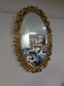 A contemporary ornate gilt framed oval mirror