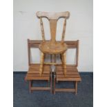 A pair of folding teak garden chairs together with a further chair