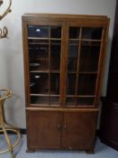 An early 20th century glazed oak bookcase fitted cupboards beneath