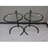 A pair of metal and glass circular lamp tables