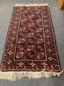 A fringed Afghan Bokhara rug on red ground,