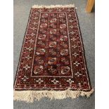 A fringed Afghan Bokhara rug on red ground,