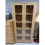 A contemporary oak effect glazed double door bookcase