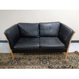 A Danish Stouby black leather two seater wooden framed settee