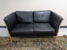 A Danish Stouby black leather two seater wooden framed settee