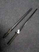 A reproduction samurai sword in scabbard on display stand