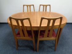 A teak veneered oval extending dining table together with a set of six rail back dining chairs