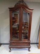 A contemporary hardwood glazed double door bookcase on claw and ball feet