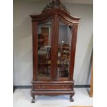 A contemporary hardwood glazed double door bookcase on claw and ball feet