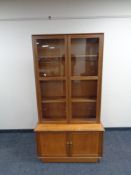 A glazed teak bookcase fitted cupboards beneath