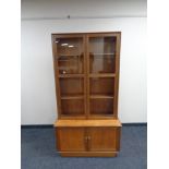 A glazed teak bookcase fitted cupboards beneath