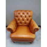 A tan leather buttoned armchair