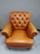 A tan leather buttoned armchair