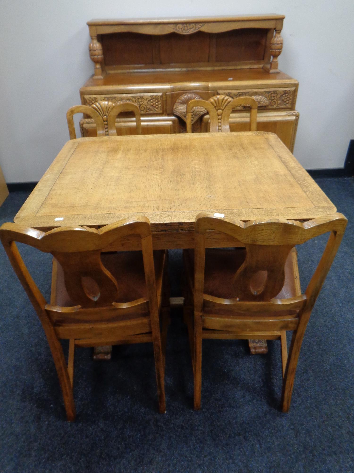 A 1930s heavily carved oak buffet sideboard together with matching pull out dining table and set of