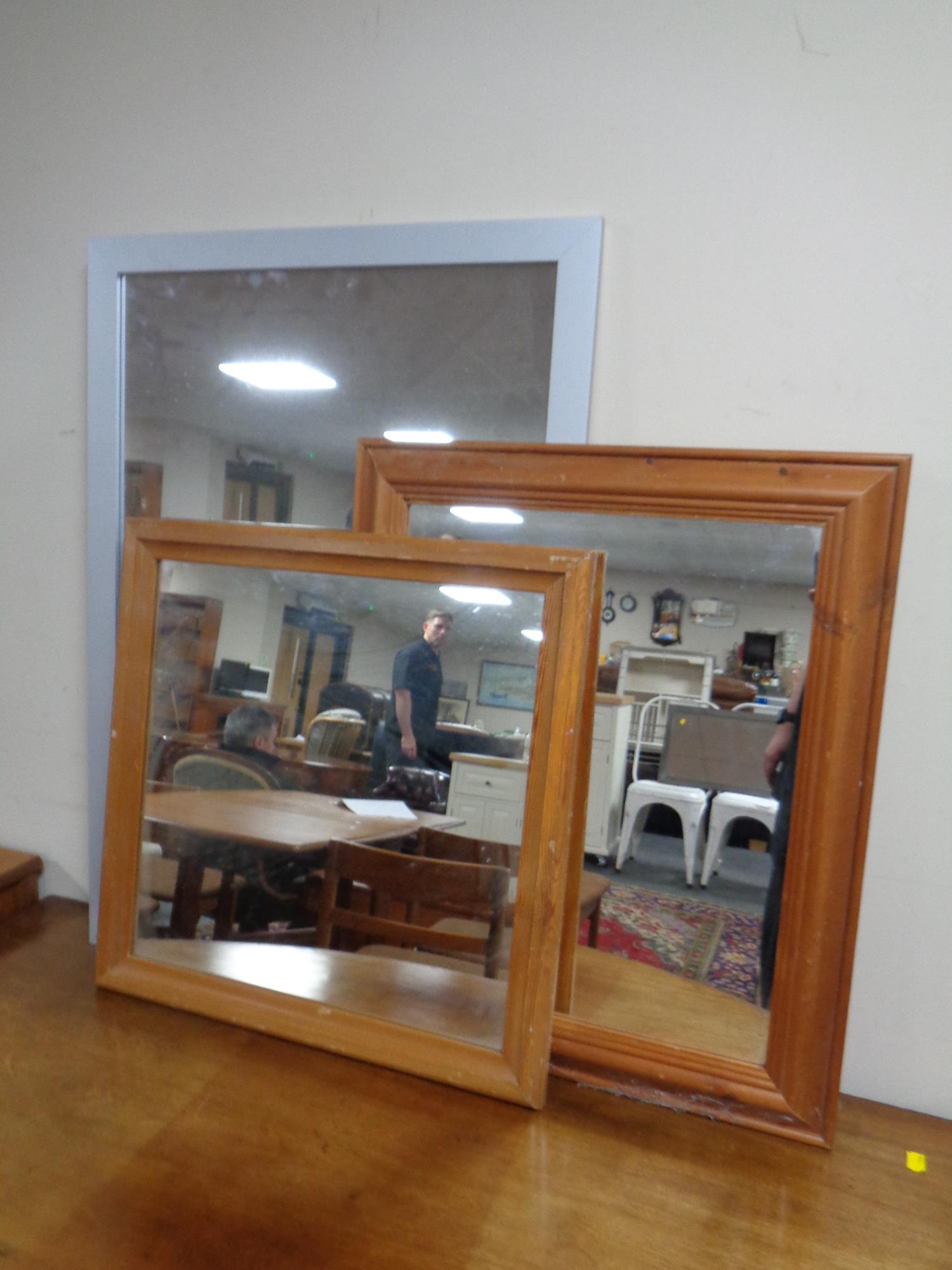 Two pine framed mirrors together with a further silvered framed mirror
