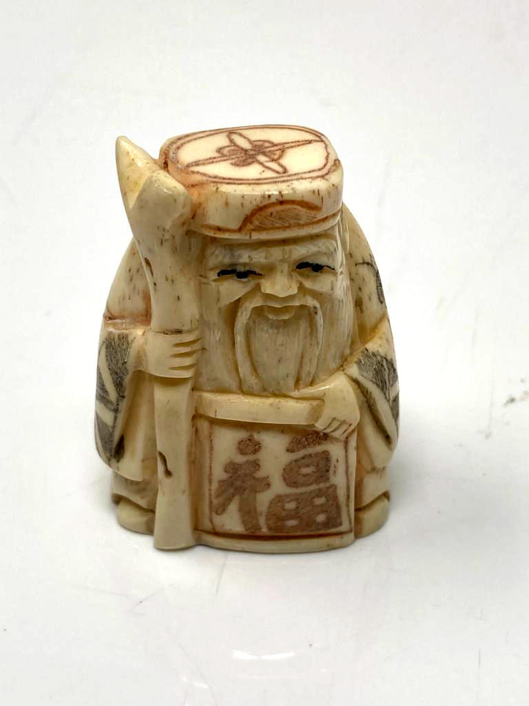 A carved Chinese bone netsuke - village elder with scroll and staff