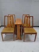 A 20th century teak drop leaf dining table together with a set of four chairs in beige upholstery