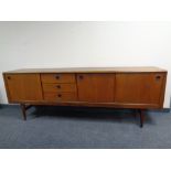 A 20th century teak low sideboard fitted sliding cupboard doors and drawers beneath