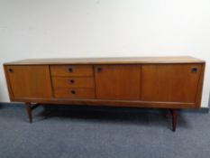 A 20th century teak low sideboard fitted sliding cupboard doors and drawers beneath