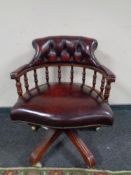 A Chesterfield style swivel desk chair in burgundy leather upholstery