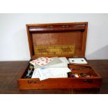 An Edwardian mahogany games box containing drafts, counters, cards,