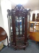 A contemporary carved hardwood bow fronted glazed display cabinet