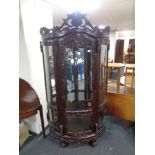A contemporary carved hardwood bow fronted glazed display cabinet