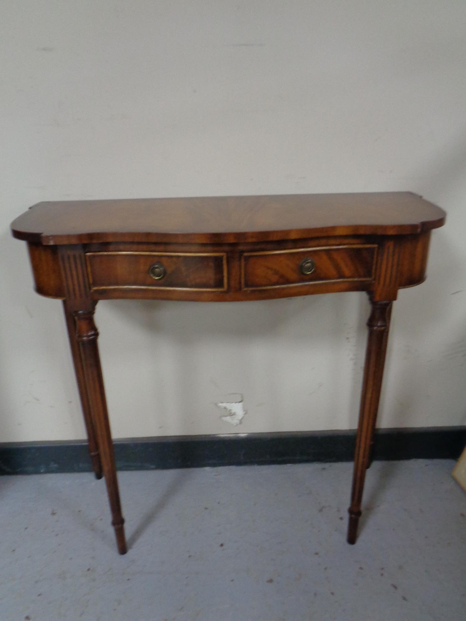 A reproduction mahogany serpentine front two drawer side table