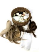 A small basket containing doll accessories and parts including wigs, clothing etc.