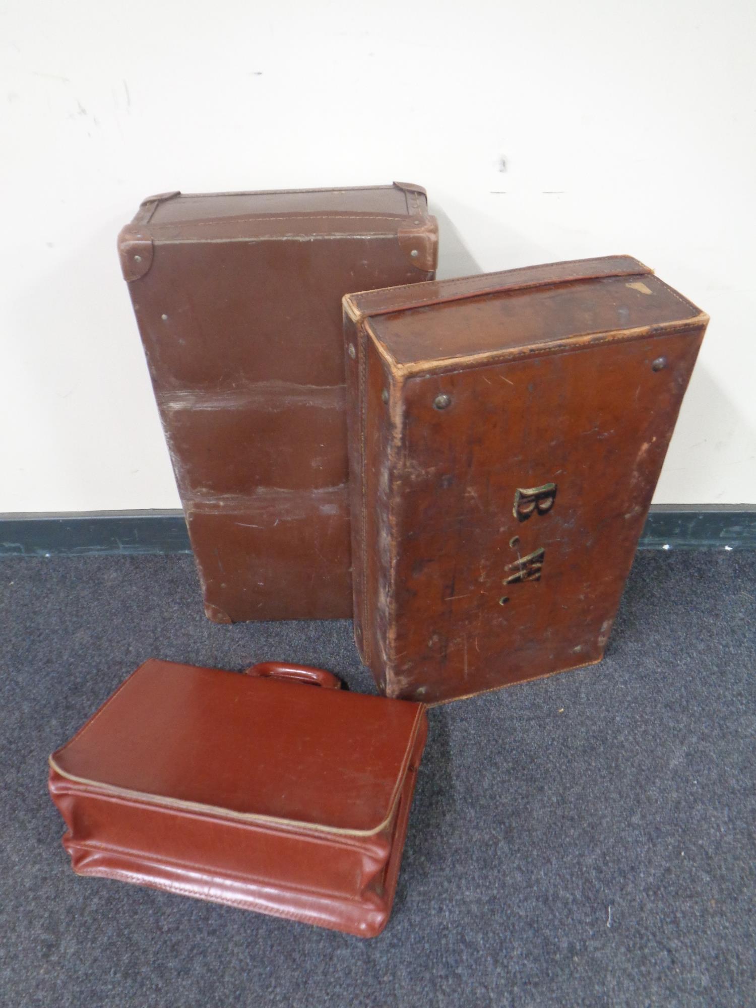 A vintage leather luggage case together with another case and a leather brief case