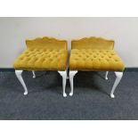 A pair of dressing table stools upholstered in gold buttoned dralon on painted legs