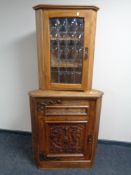 An Arts and Crafts corner cabinet with a carved panel door together with a further wall mounted
