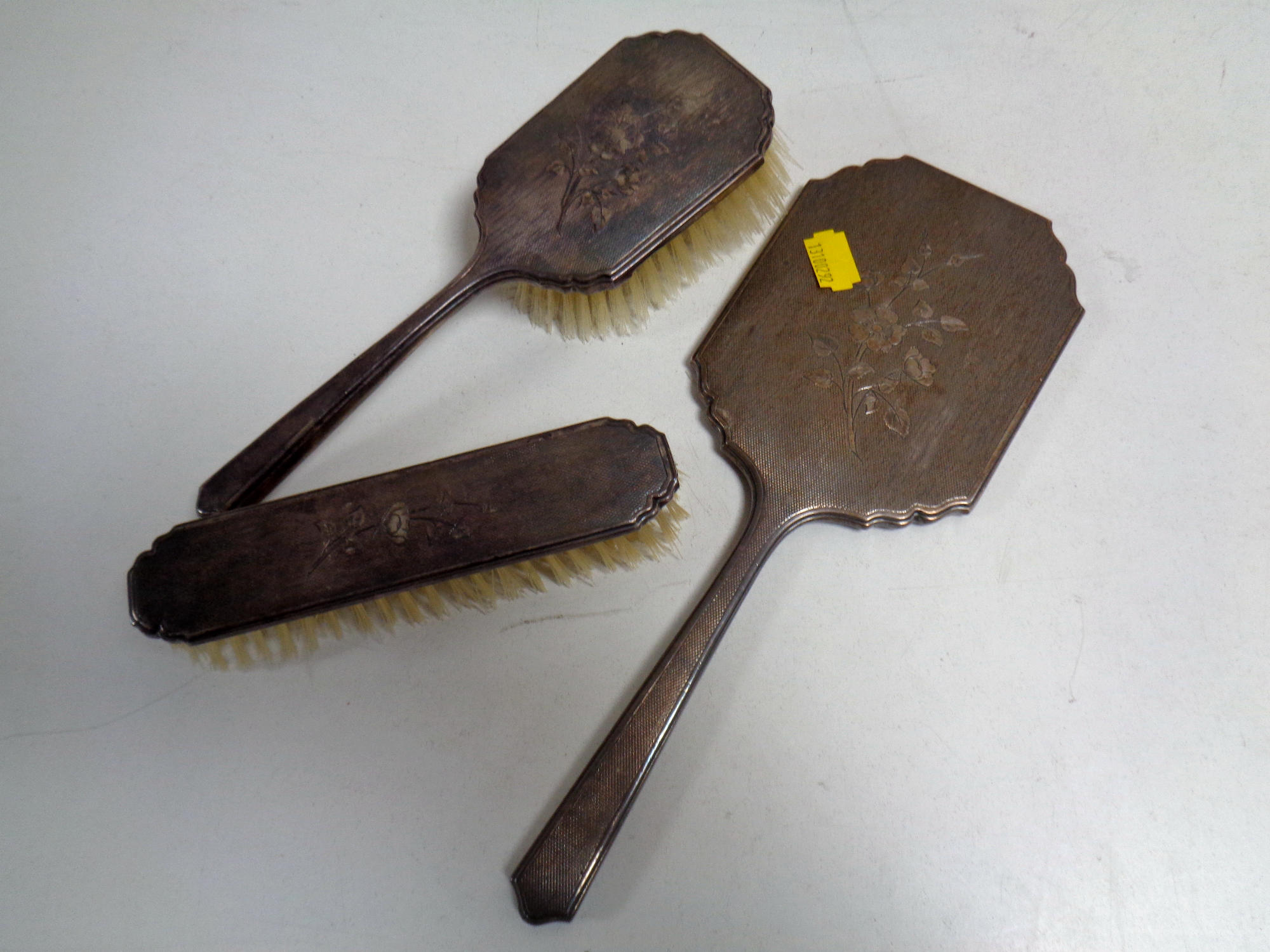 A three piece silver backed dressing table brush and hand mirror set.