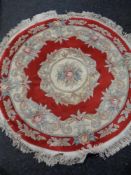 A circular fringed Chinese rug on red ground.