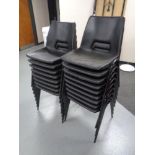 Seventeen black plastic stacking chairs.