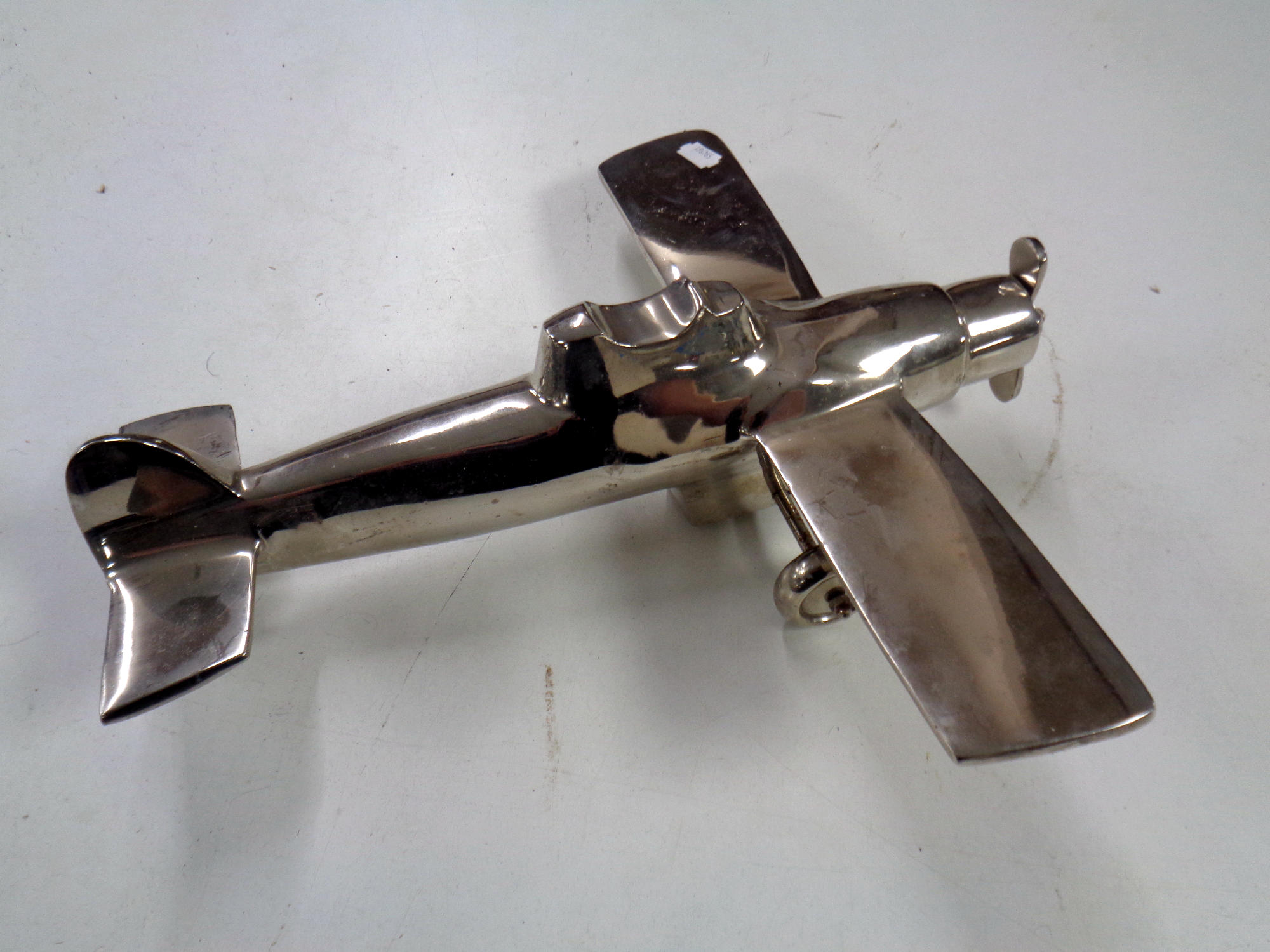 A chromed metal model of an aeroplane CONDITION REPORT: Missing one wheel.