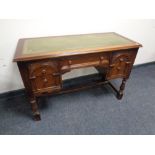 An oak five drawer knee hole desk with tooled leather panel