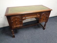 An oak five drawer knee hole desk with tooled leather panel