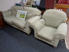 A two seater settee and matching armchair upholstered in a green and gold classical floral print