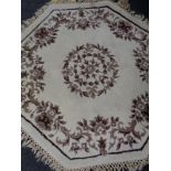 A hexagonal floral fringed rug on cream ground.