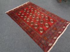 A Bokhara rug, Afghanistan, with repeat gul motif on red ground, 237cm by 144cm.