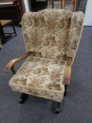 A tapestry upholstered wingback rocking chair.