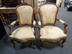 A pair of early 20th century carved beech salon armchairs upholstered in a gold floral fabric