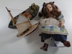 A box containing porcelain collector's doll on stand together with a wooden model of a fishing